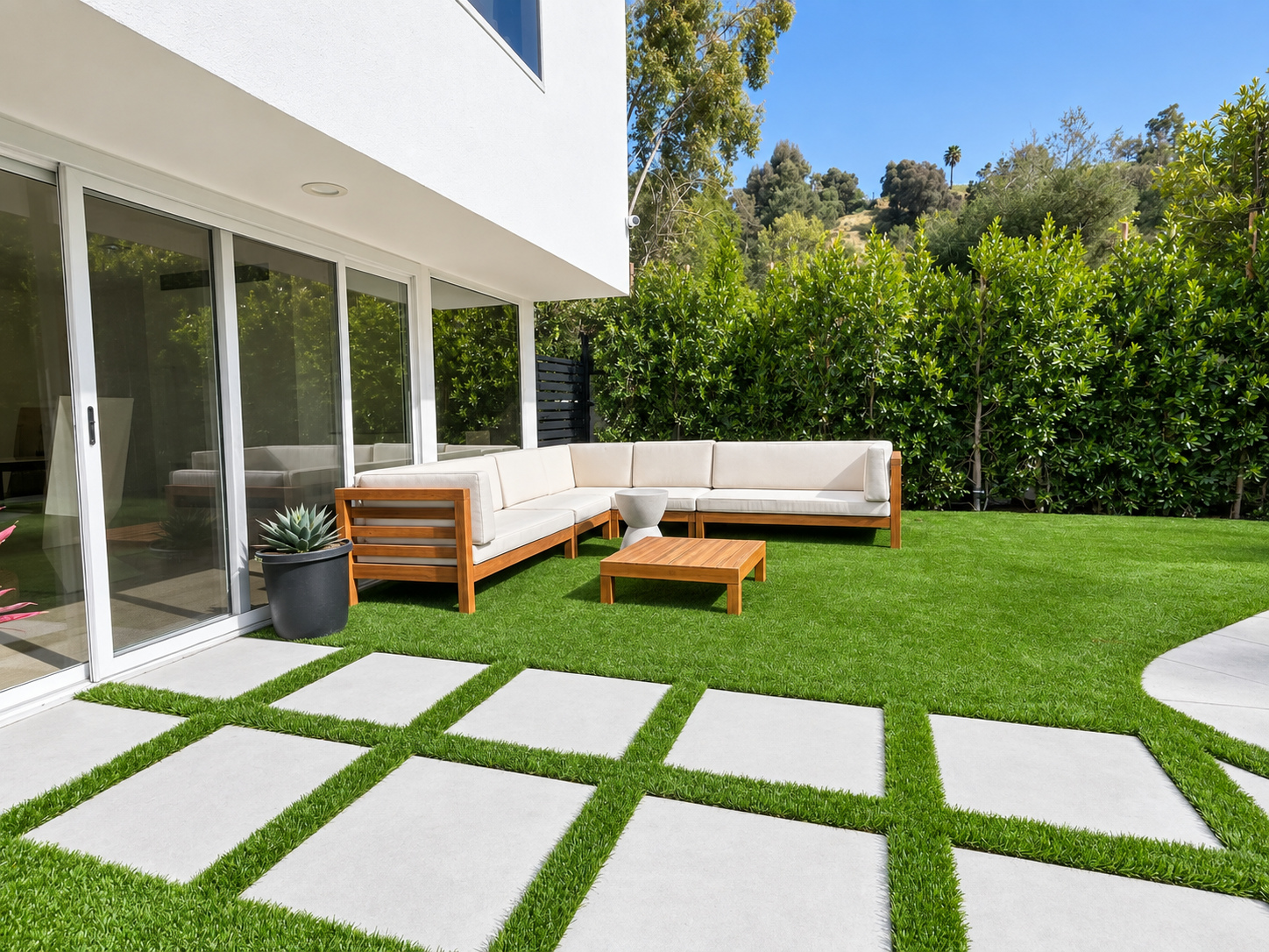 Artificial turf lawn with large concrete pads set into it beside a modern home