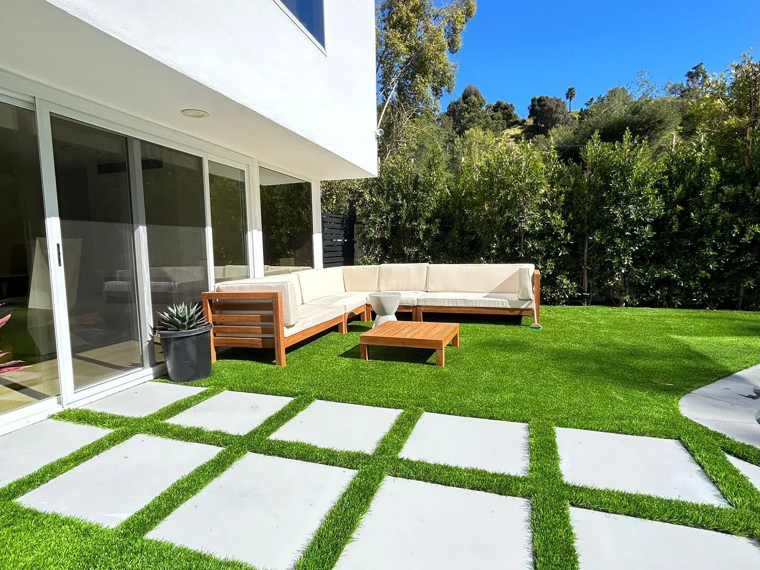 Artificial turf lawn with large concrete pads set into it beside a modern home
