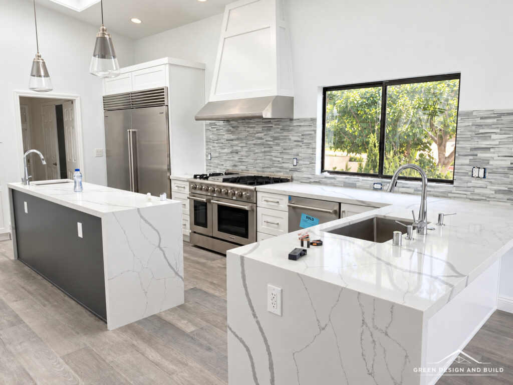 Kitchen with a white quartz waterfall island, plaster hood and professional range in a Burbank home