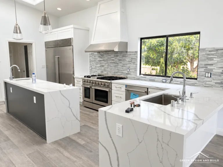 Kitchen with a white quartz waterfall island, plaster hood and professional range in a Burbank home
