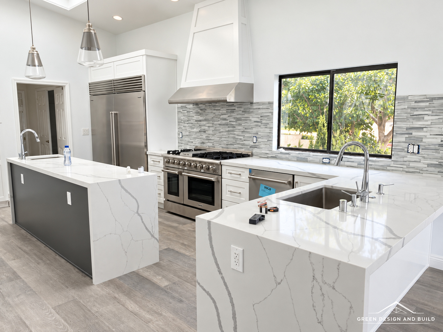 Kitchen with a white quartz waterfall island, plaster hood and professional range in a Burbank home