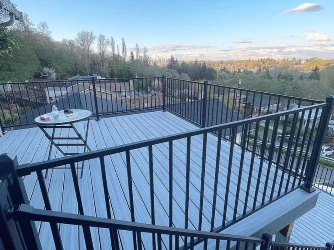 Elevated composite deck with black metal railing and an open view, built by Green Design and Build