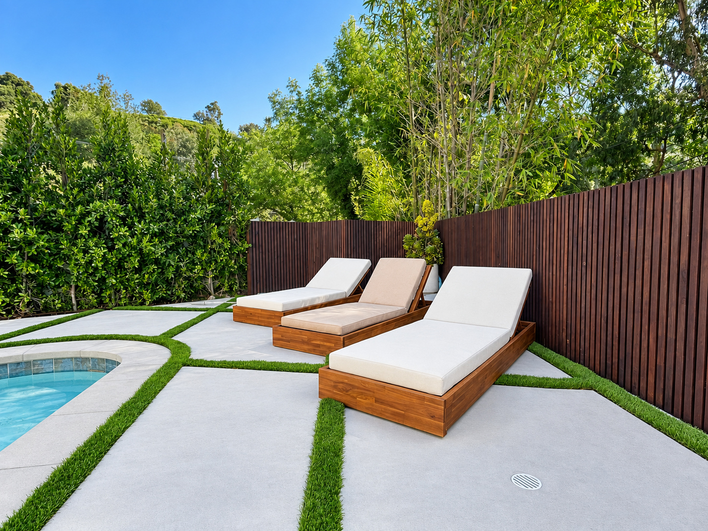 Poolside patio of large concrete pads set with turf joints, with timber loungers