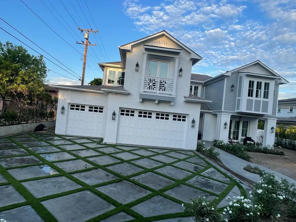 Large-format concrete paver driveway with turf joints leading to a three-car garage, built by Green Design and Build