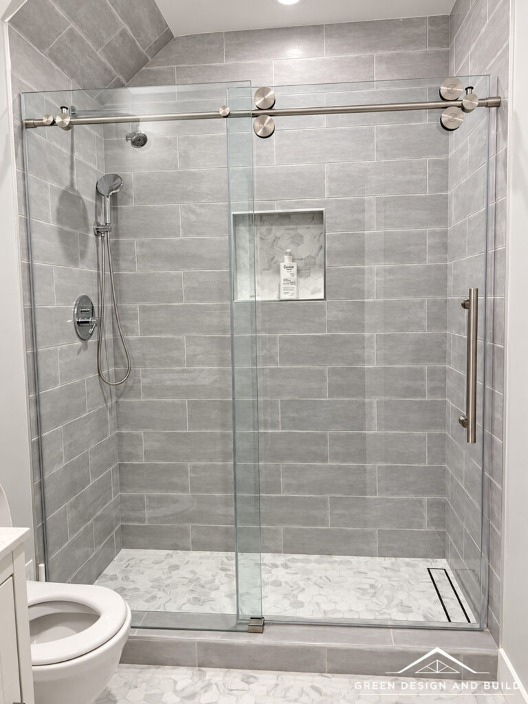 Walk-in shower with gray stone-look tile, a recessed niche and sliding glass in a Diamond Bar bathroom