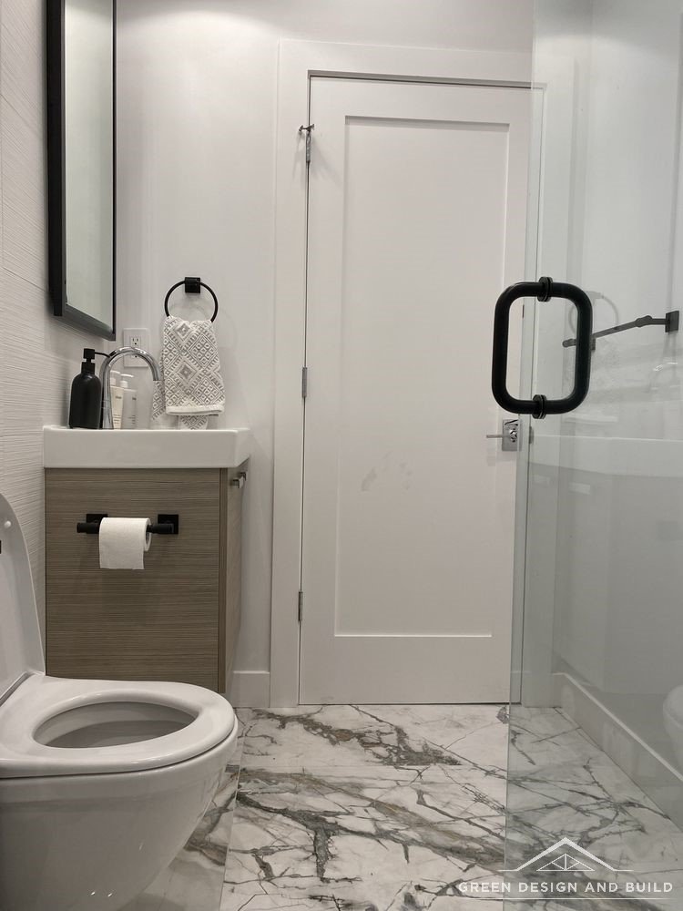 Compact bathroom with a wall-hung vanity, mirror and frameless glass shower door in a Diamond Bar home