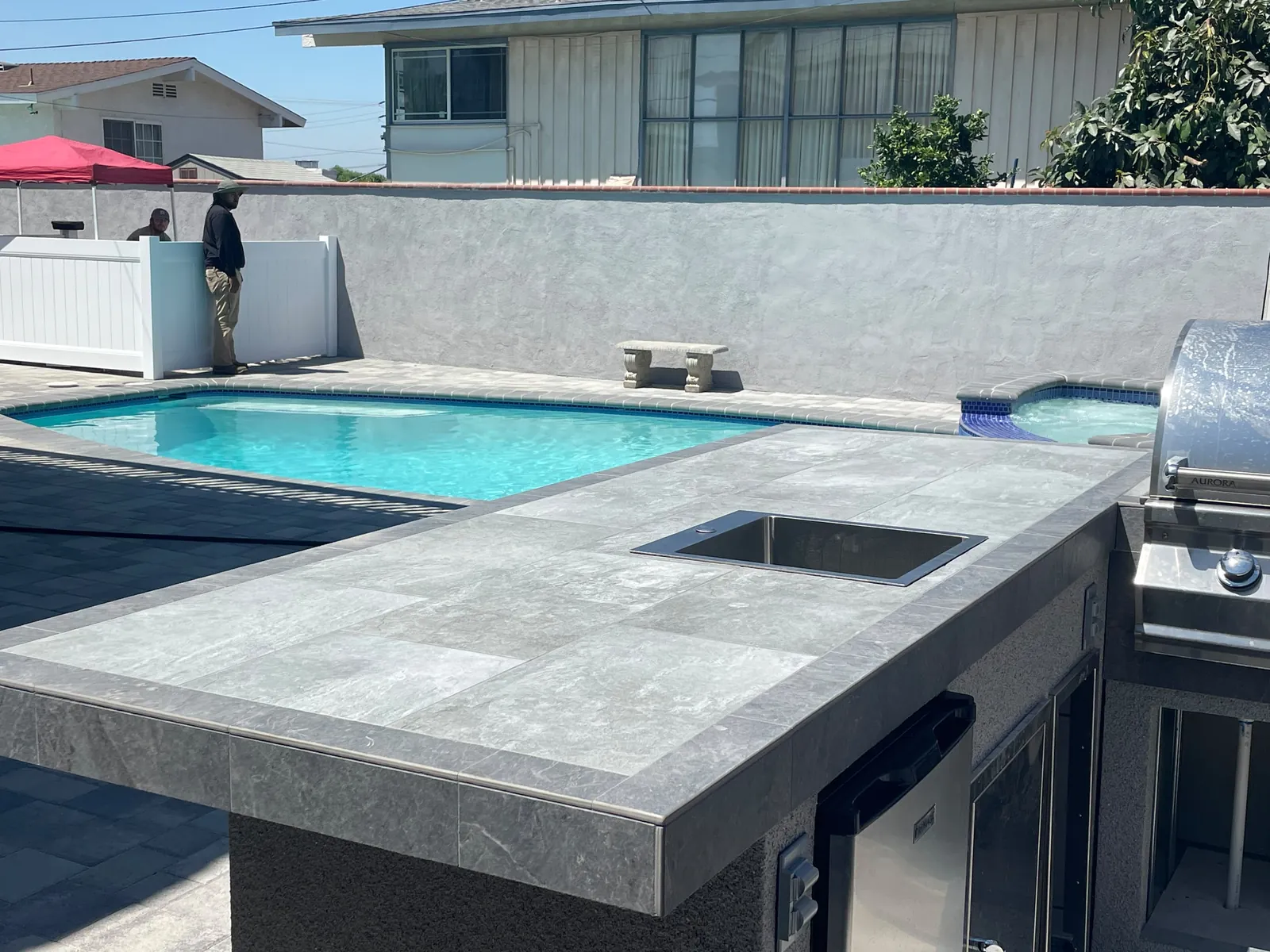Pool, spa and built-in outdoor kitchen seen together across the finished backyard