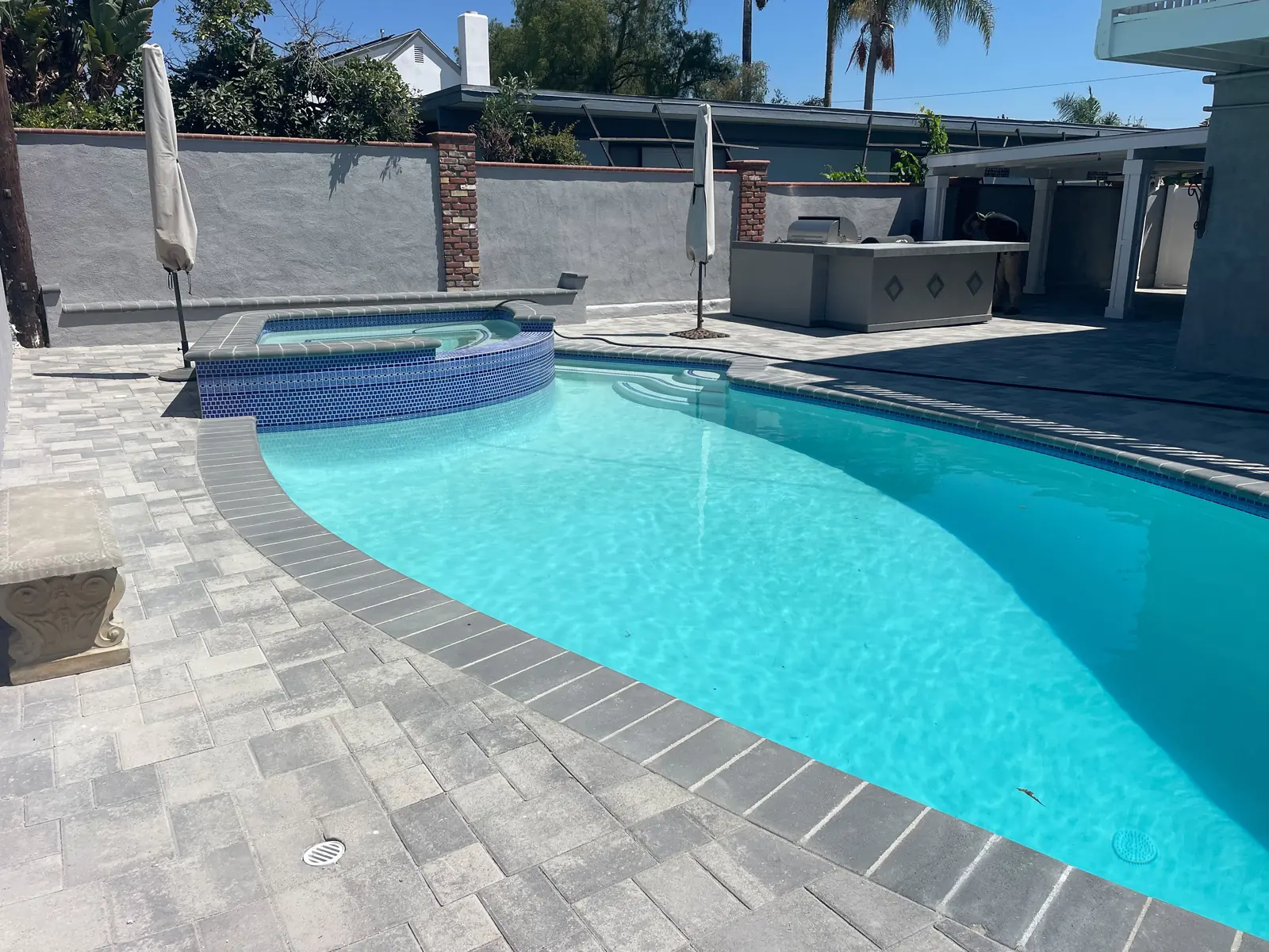 Completed pool running the length of the Encino backyard with paver decking on all sides