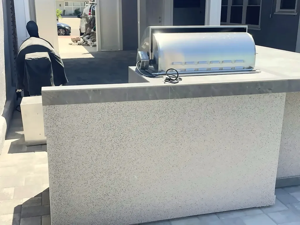 Built-in grill and tiled island counter in the finished outdoor kitchen