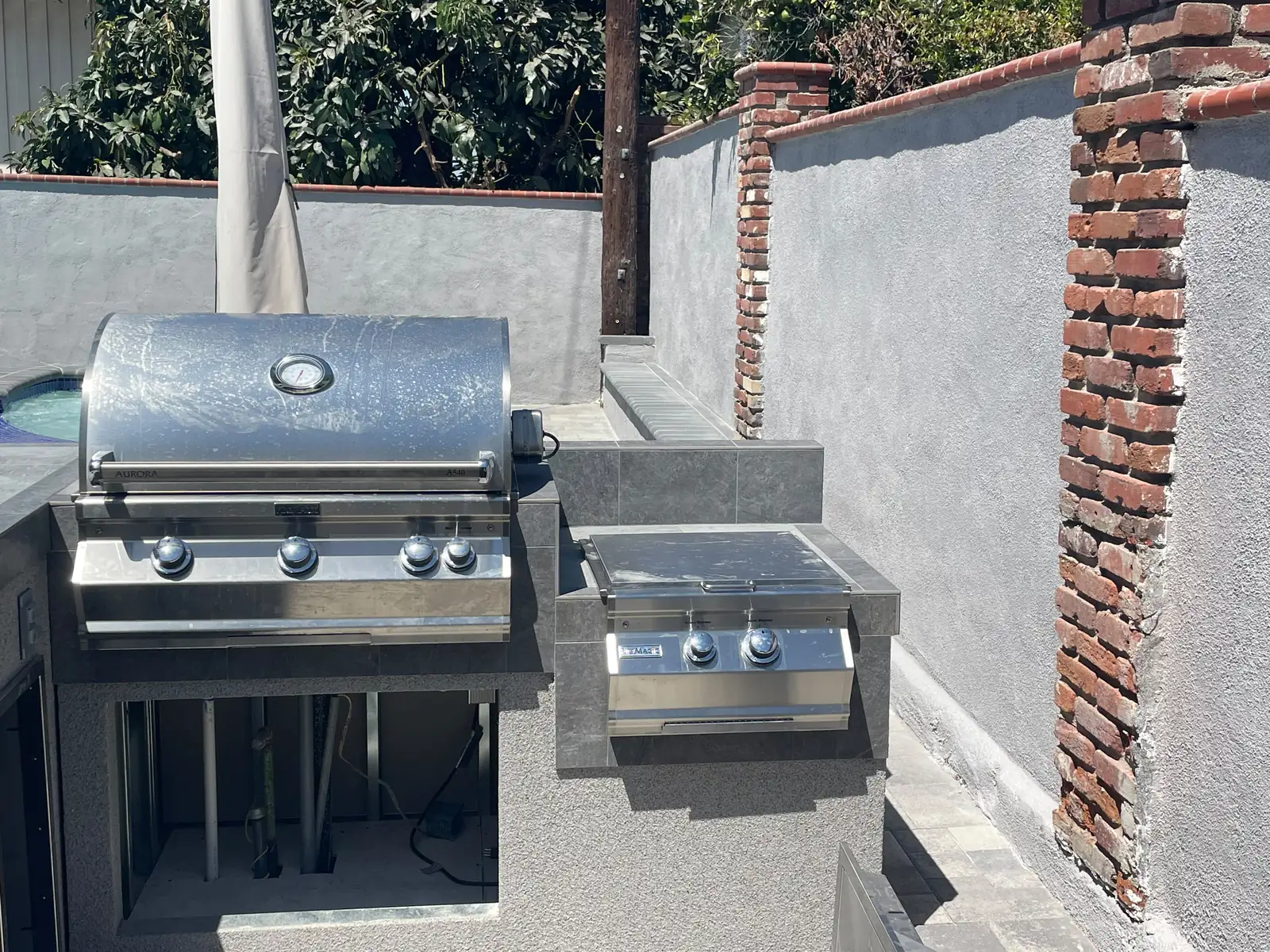 Built-in outdoor kitchen with stainless grill, side burner and sink set into a tiled counter