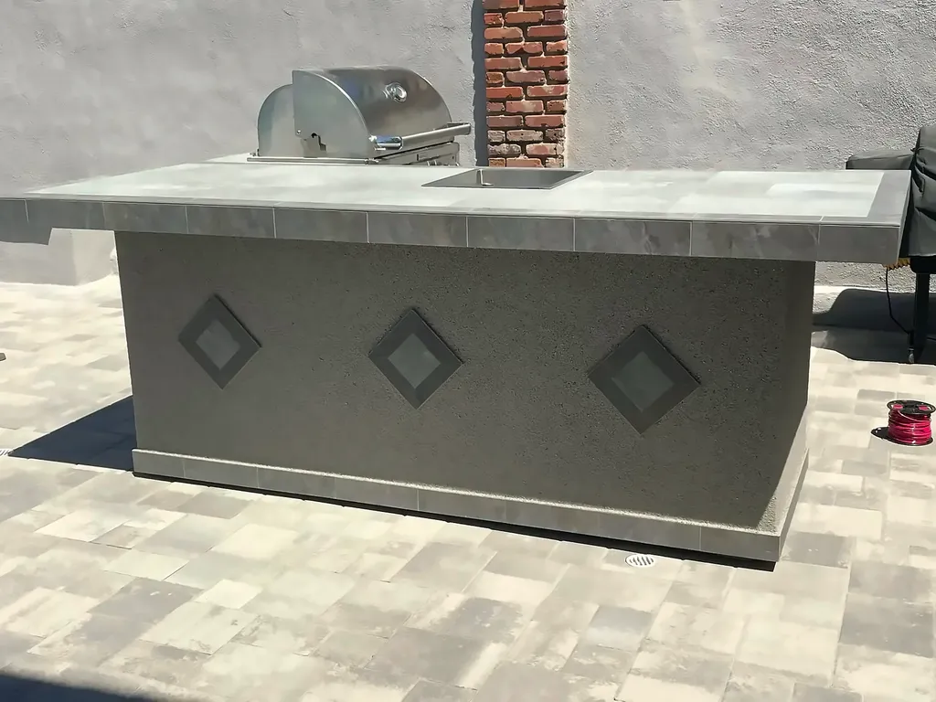 Finished outdoor kitchen island with tiled counter against the brick pilaster