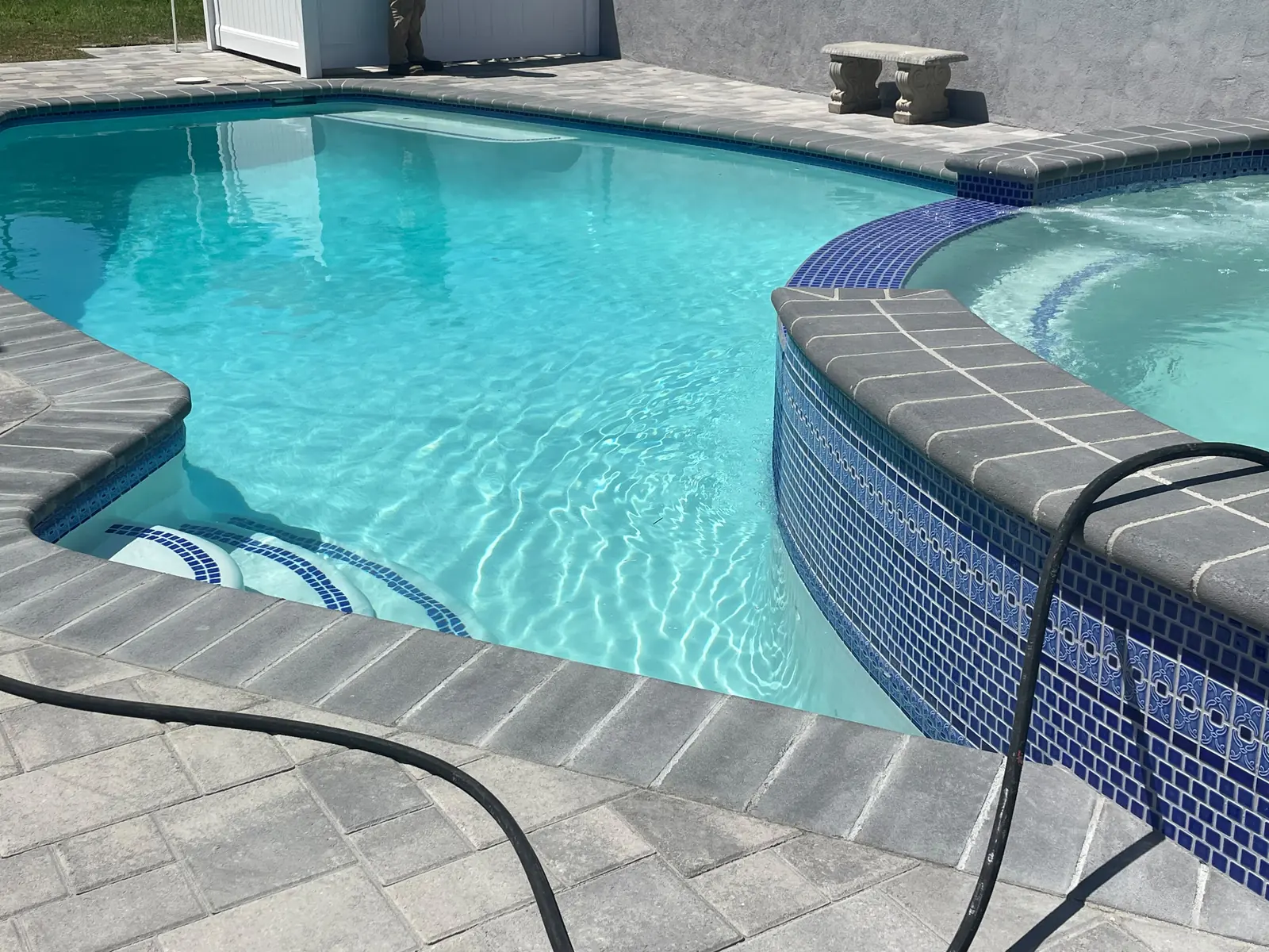 Finished pool and raised spillover spa seen from the paver deck