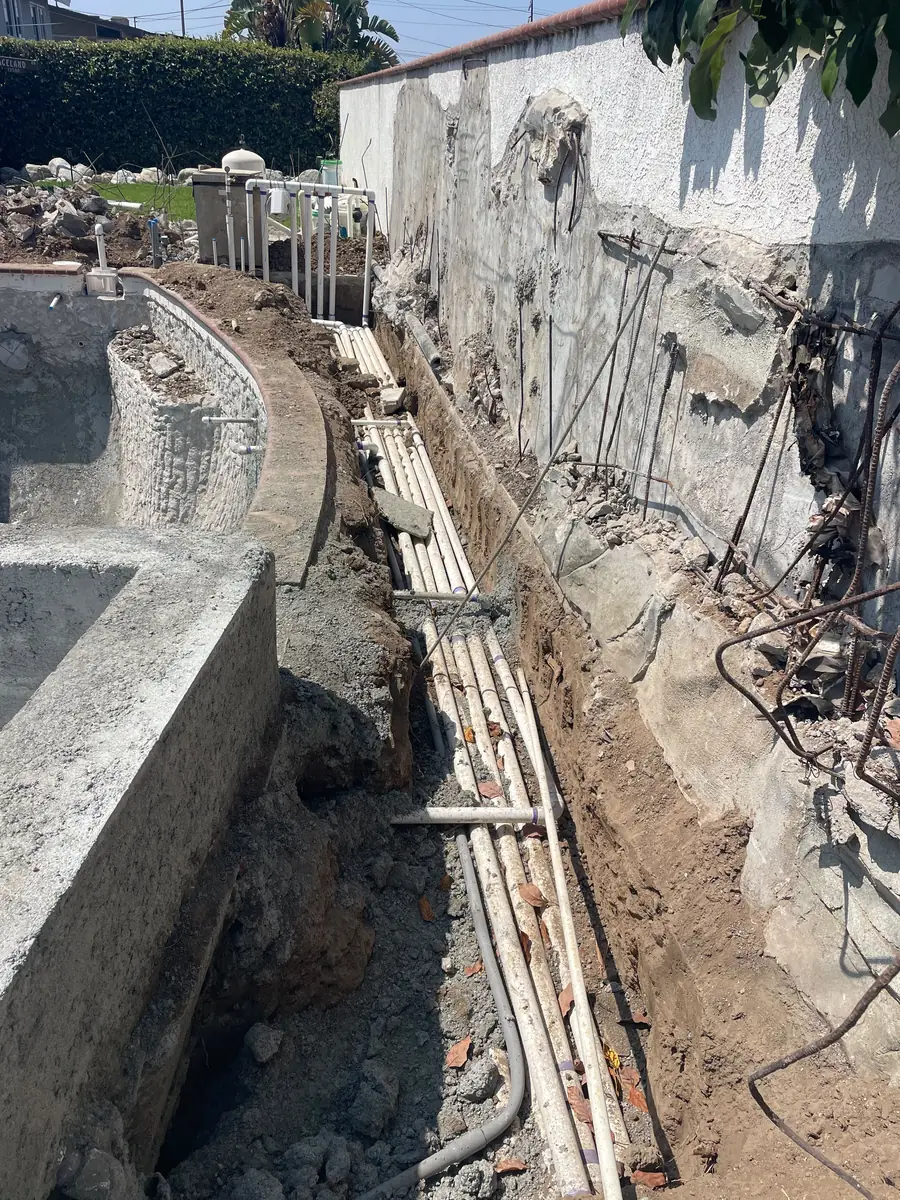 Plumbing runs trenched along the perimeter wall before backfill