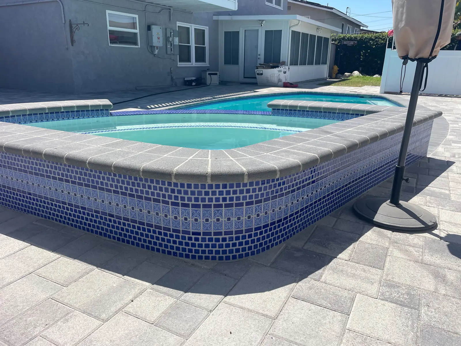 Raised spa finished in blue mosaic tile, seen from the deck