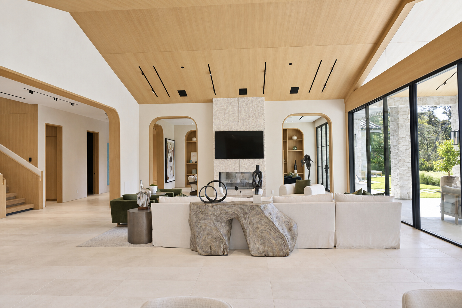 Great room with a vaulted white oak ceiling, stone fireplace and floor-to-ceiling sliding glass doors