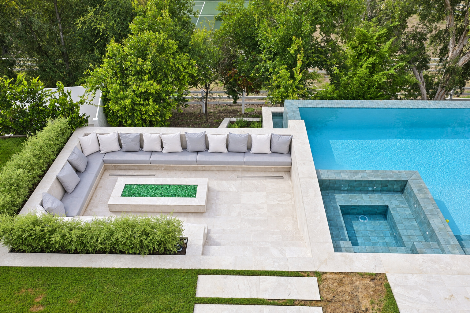 Backyard with an infinity-edge pool, tiled spa and a sunken stone lounge around a fire feature