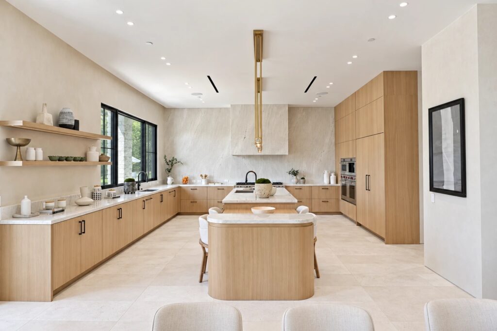 Modern white oak kitchen with a stone slab backsplash, brass pendant and a rounded island with seating