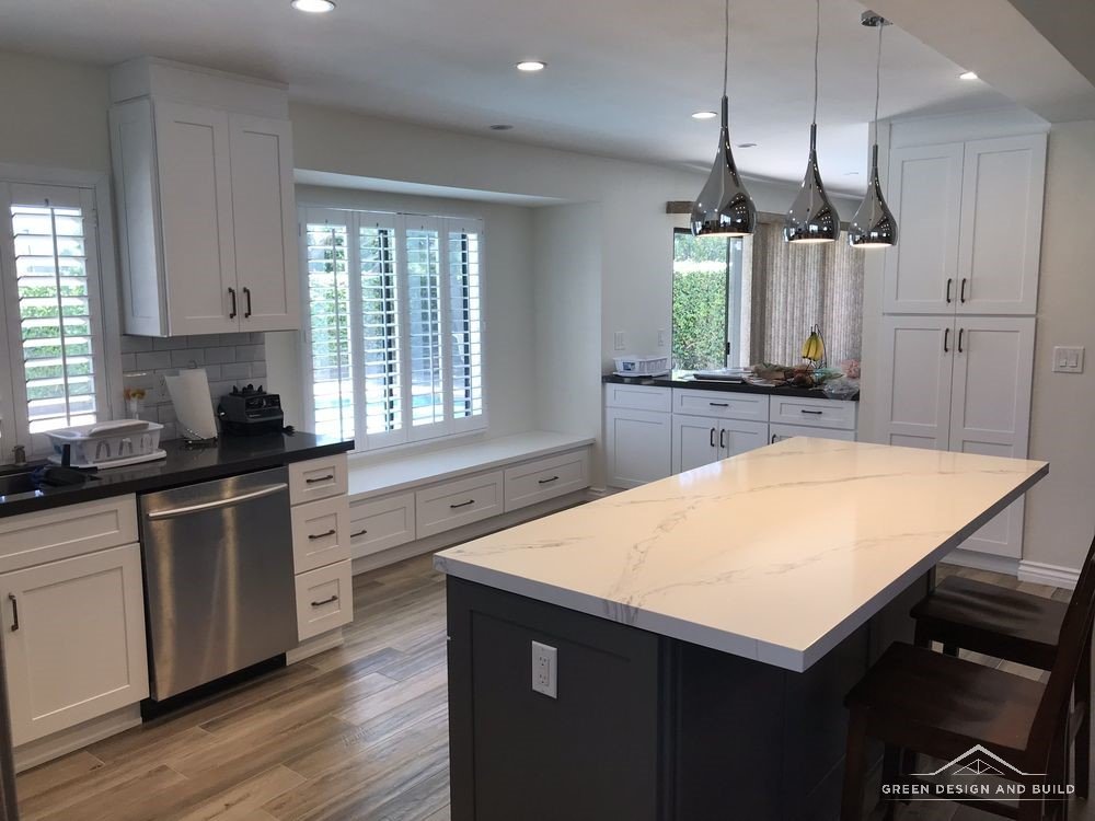 Finished kitchen with a marble-look island, pendant lights and plantation shutters in a Manhattan Beach home