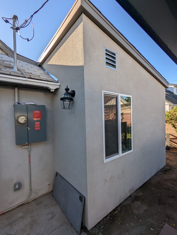 Finished stucco exterior of a rear room addition with its own electrical panel at a Montebello home