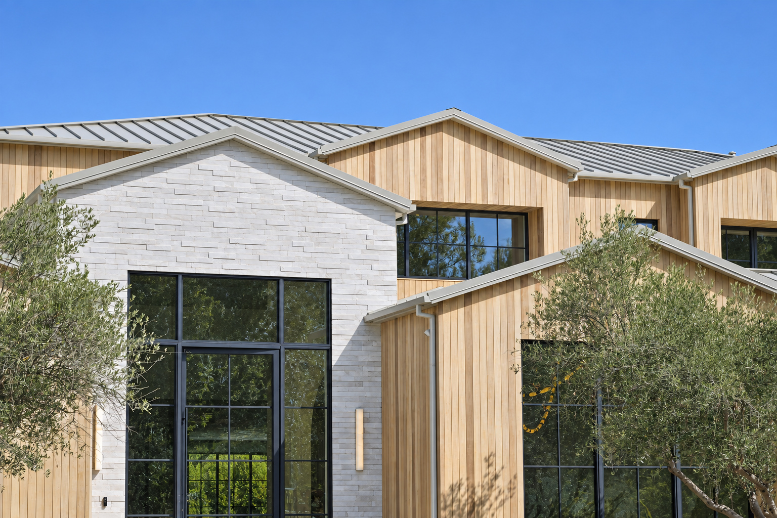 Standing seam metal roof over cedar siding and white stone on a custom home built by Green Design and Build in Hidden Hills