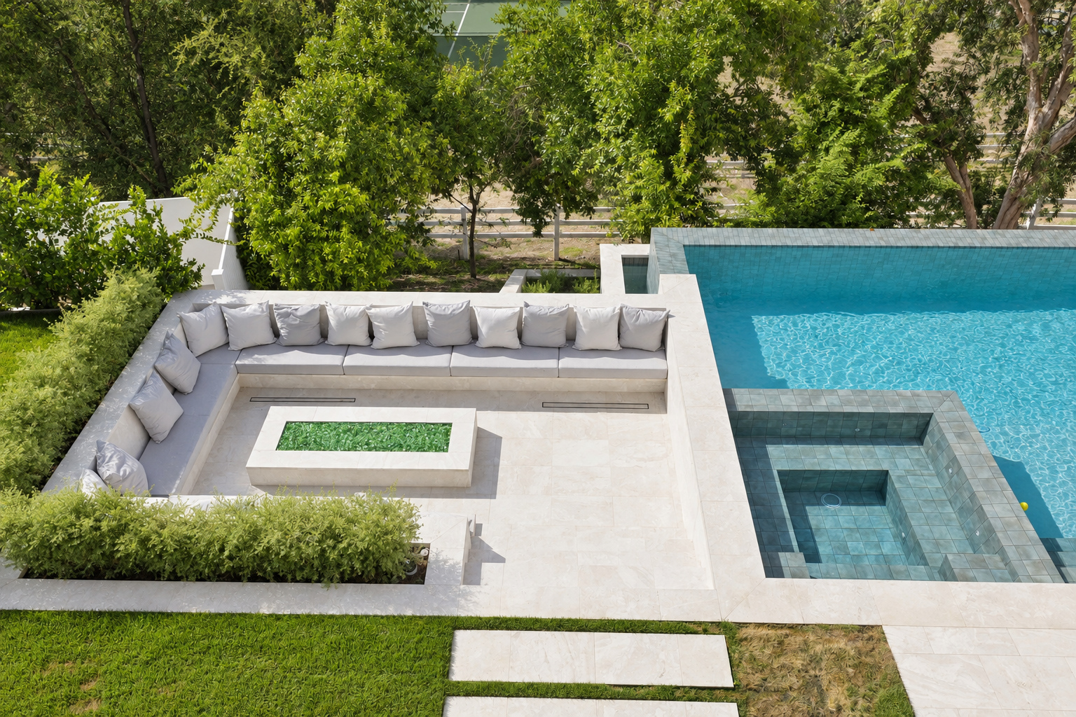 Sunken fire pit lounge with built-in concrete seating beside an infinity-edge pool and raised spa in Hidden Hills