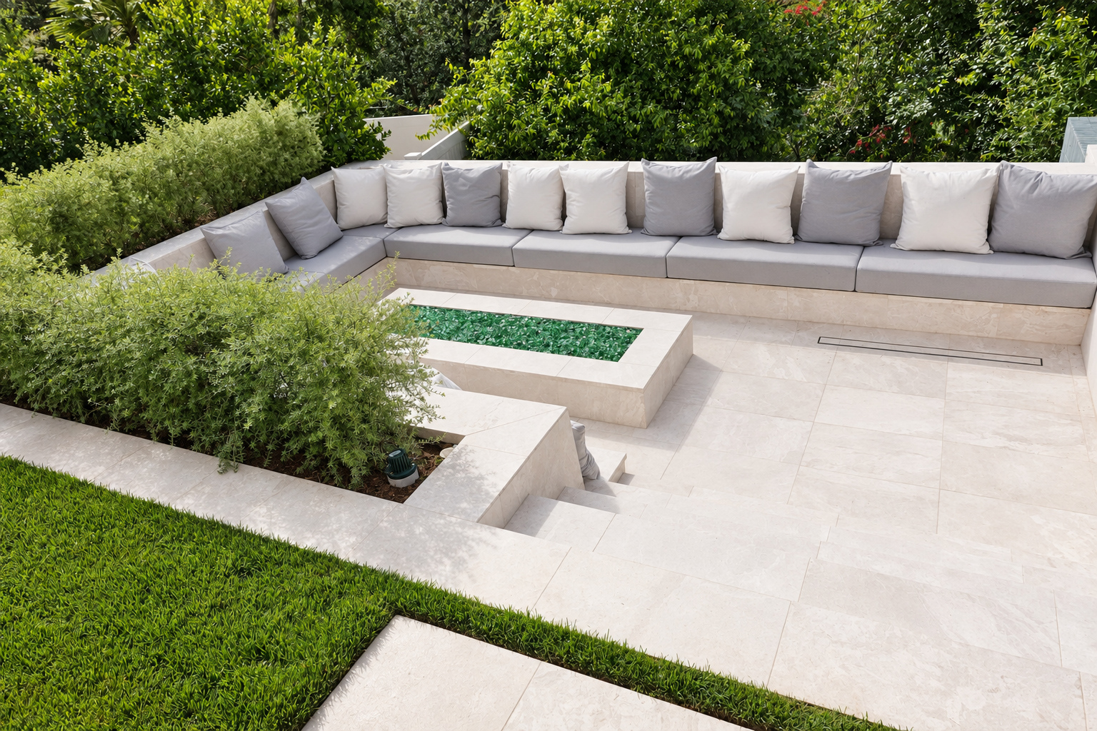 Sunken seating area with poured concrete bench and fire table set into a large-format stone patio in Hidden Hills
