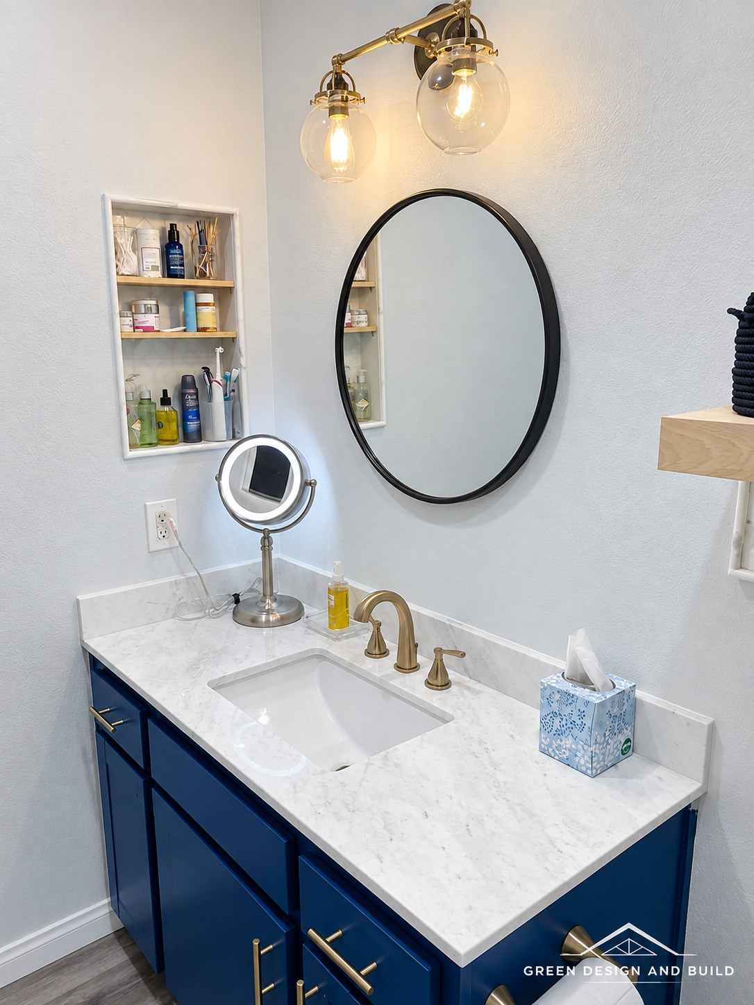 Round black mirror flanked by Edison bulb sconces above a navy vanity in West Hollywood