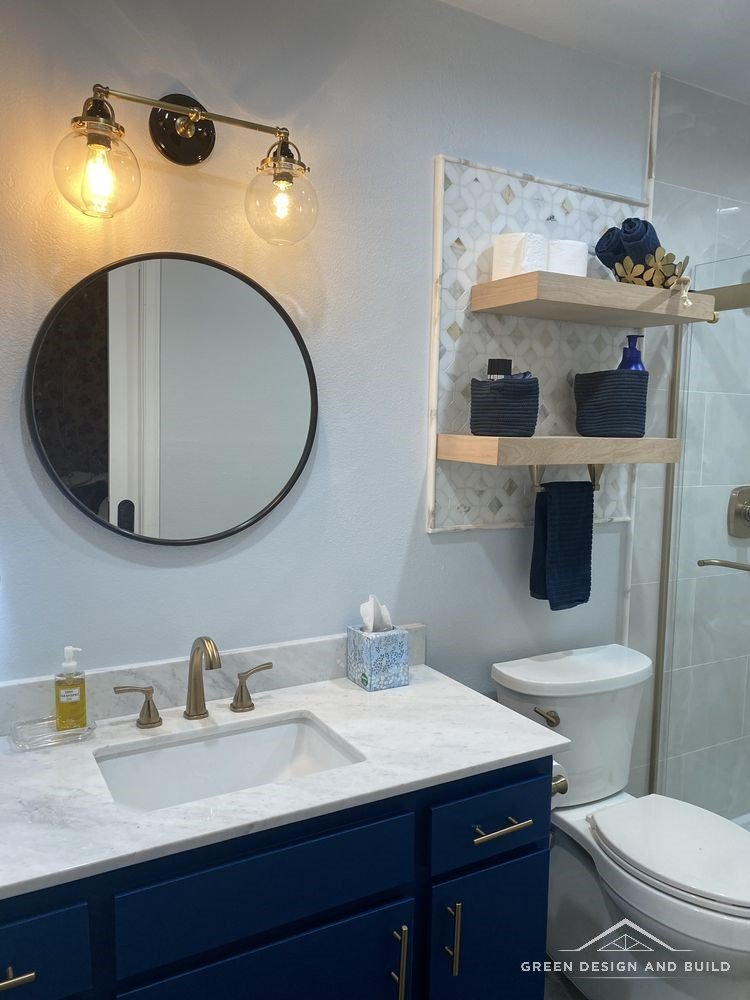 Navy shaker vanity with brass hardware, marble-look counter and a round black mirror in a West Hollywood bathroom