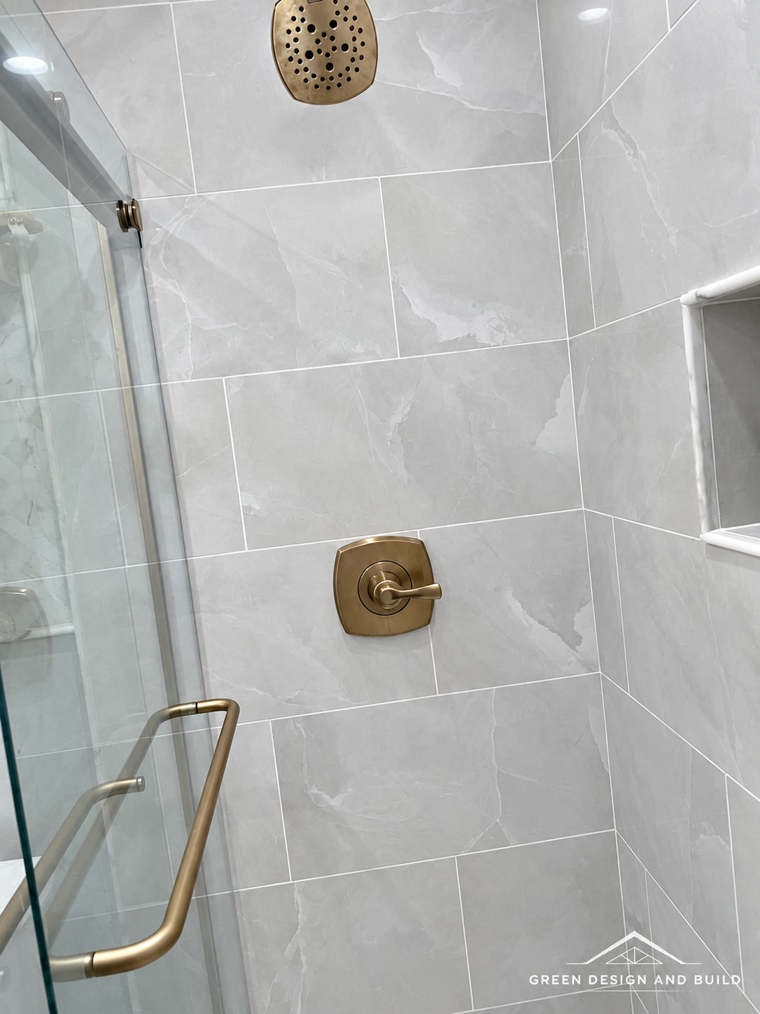 Gray tiled shower with brass fittings behind sliding glass in a West Hollywood bathroom