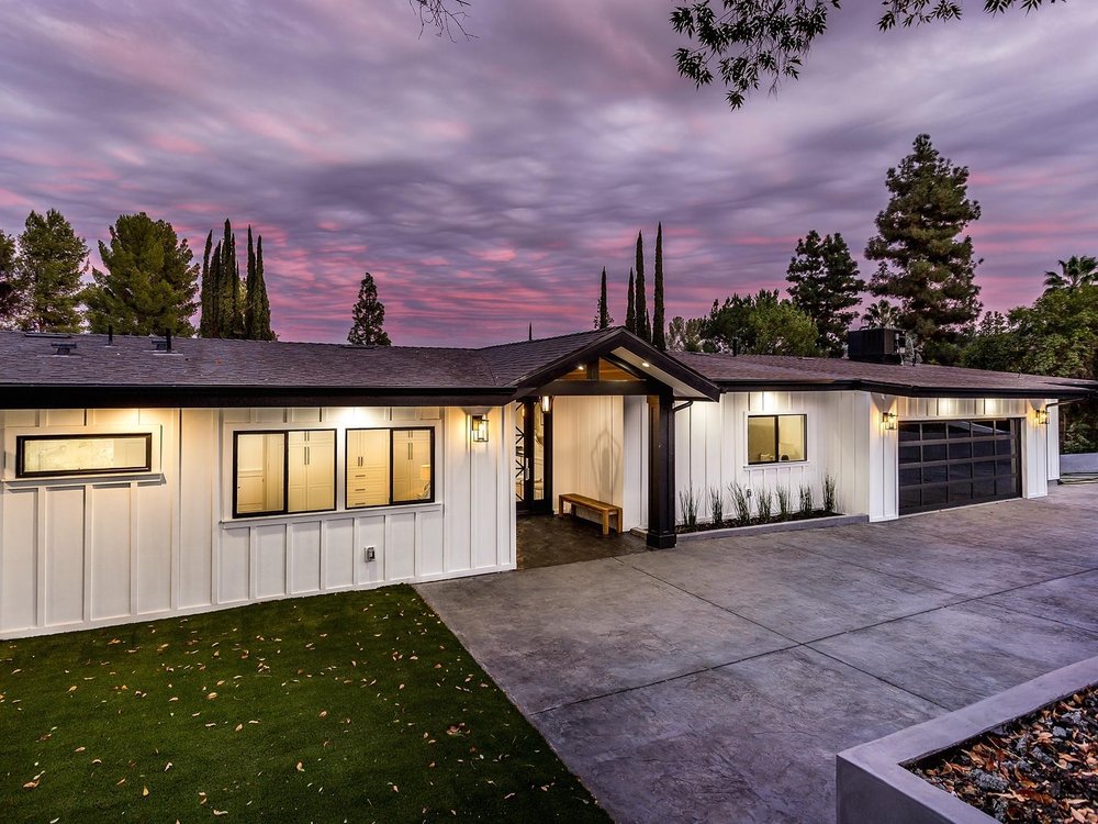 Finished white board-and-batten front elevation of a rebuilt Woodland Hills ranch home at dusk