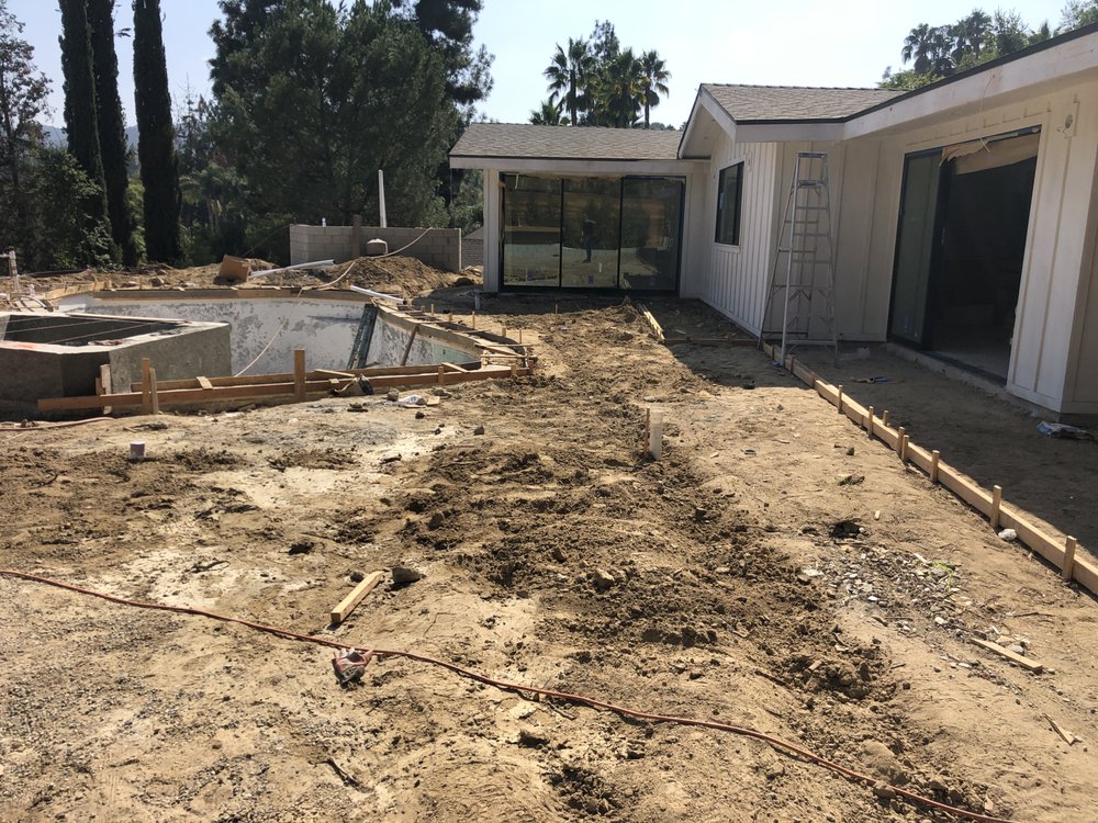 Rear yard of a Woodland Hills house cleared to bare soil at the start of a whole-home rebuild by Green Design and Build